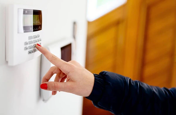 Hand entering code on a home burglar alarm keypad system.