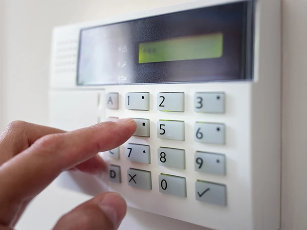 Person entering security code on advanced burglar alarm keypad in Wellington FL home.