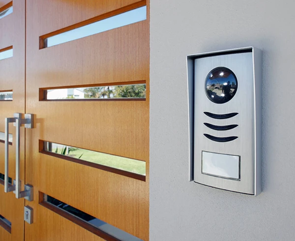 Modern wireless doorbell intercom system installed next to a wooden front door, showcasing benefits of wireless burglar alarm systems in Palm Beach Island, FL.
