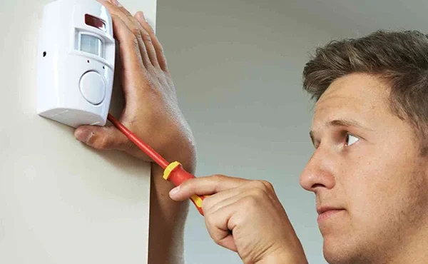 Technician installing a burglar alarm system for home security.