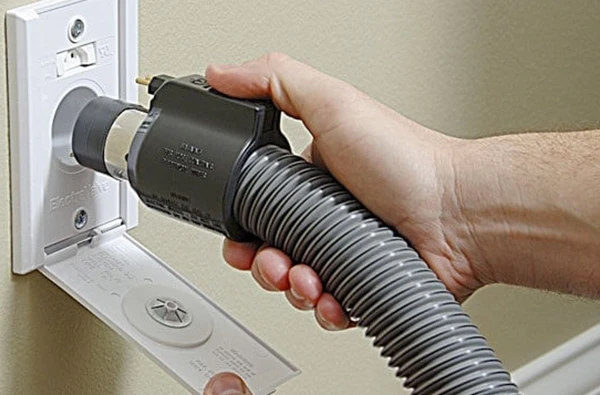 Person plugging a central vacuum system hose into a wall inlet, highlighting efficient central vacuum system installation in Palm Beach Island, FL.