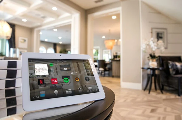 Tablet showing home automation system controls in a stylish modern living room.
