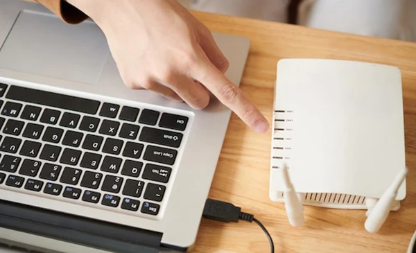 Hands typing on a laptop next to a wireless router, representing fast internet setup in Delray Beach, FL.