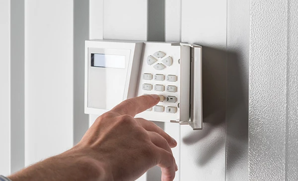 Burglar alarm keypad with a hand arming the system for enhanced security.