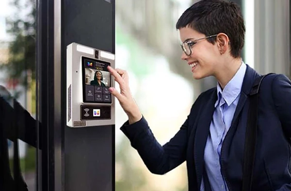 Woman accessing a touchscreen intercom panel outside a secure building, highlighting seamless intercom system installation services in Palm Beach Island, FL.