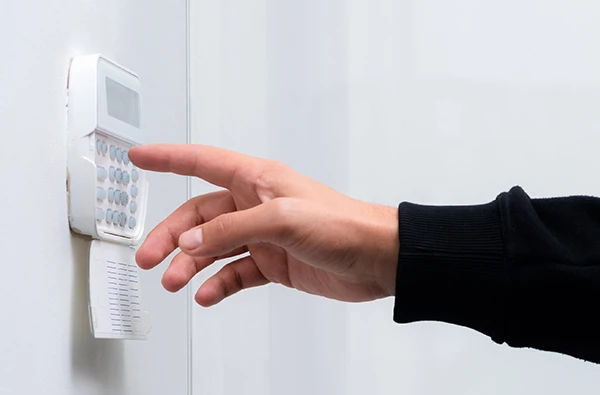 A hand entering a code on a burglar alarm keypad in a Delray Beach, FL home, ensuring security.