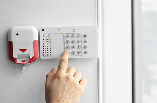 A secure burglar alarm system keypad with a hand entering the code, installed in a Boca Raton, FL, home for enhanced security.