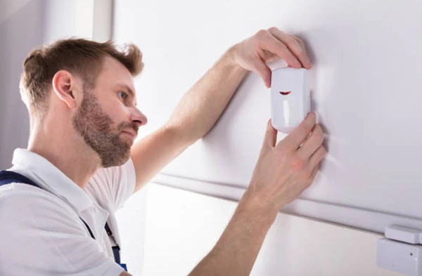 Professional installing smart security sensor in ceiling for enhanced home protection in Stuart FL.