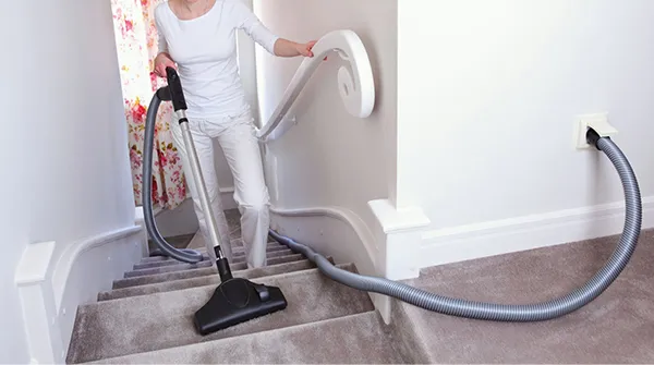 Central vacuum hose in operation near wall base, showcasing hose outlet installation in Wellington FL.