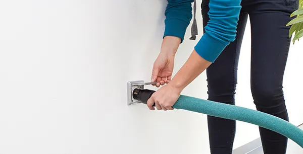 High-powered built-in central vacuum hose being connected to wall outlet in Boca Raton FL.