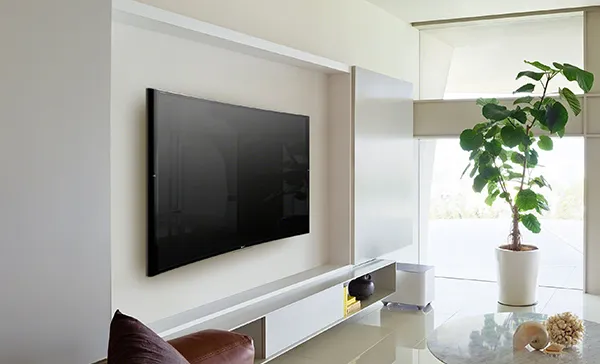 Professional flat-screen TV mounted on a clean white wall with minimalistic living room decor in Stuart, FL.