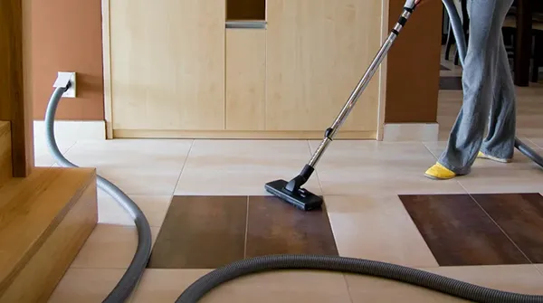 Professional whole-house central vacuum installation in Stuart FL with hose and hose attachment on hardwood floor.